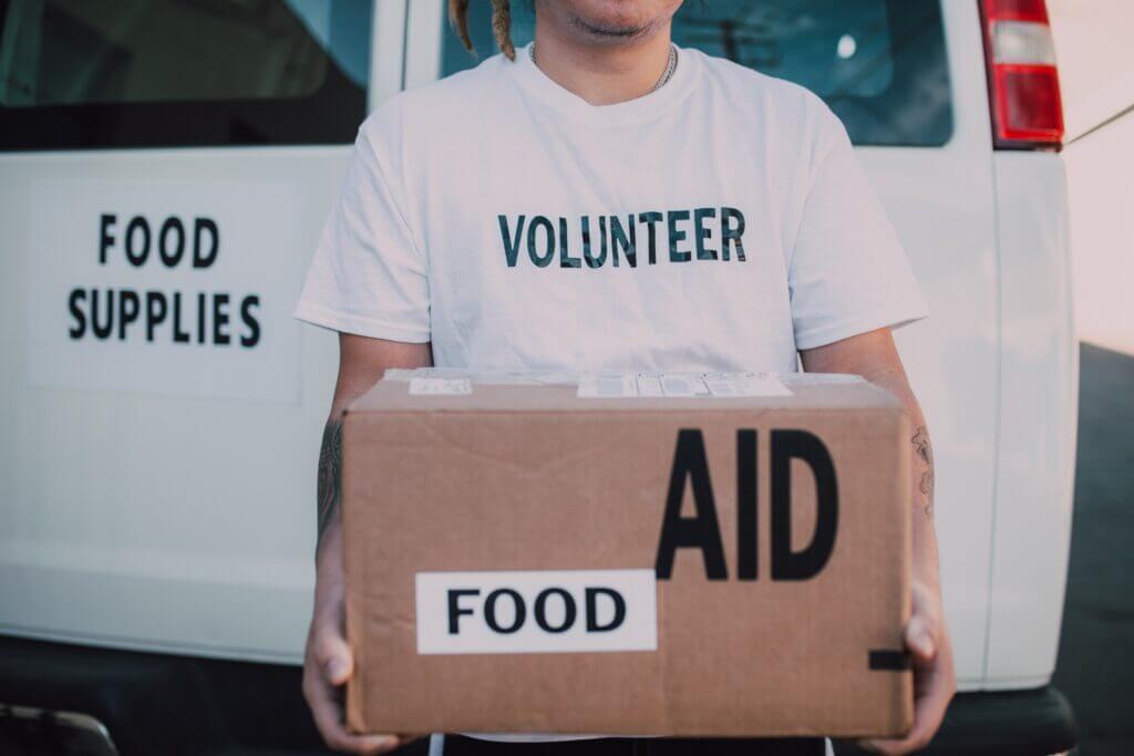 Volunteer holding a box labeled Food for nonprofit activities. Learn how nonprofits can benefit from an automated communication platform.